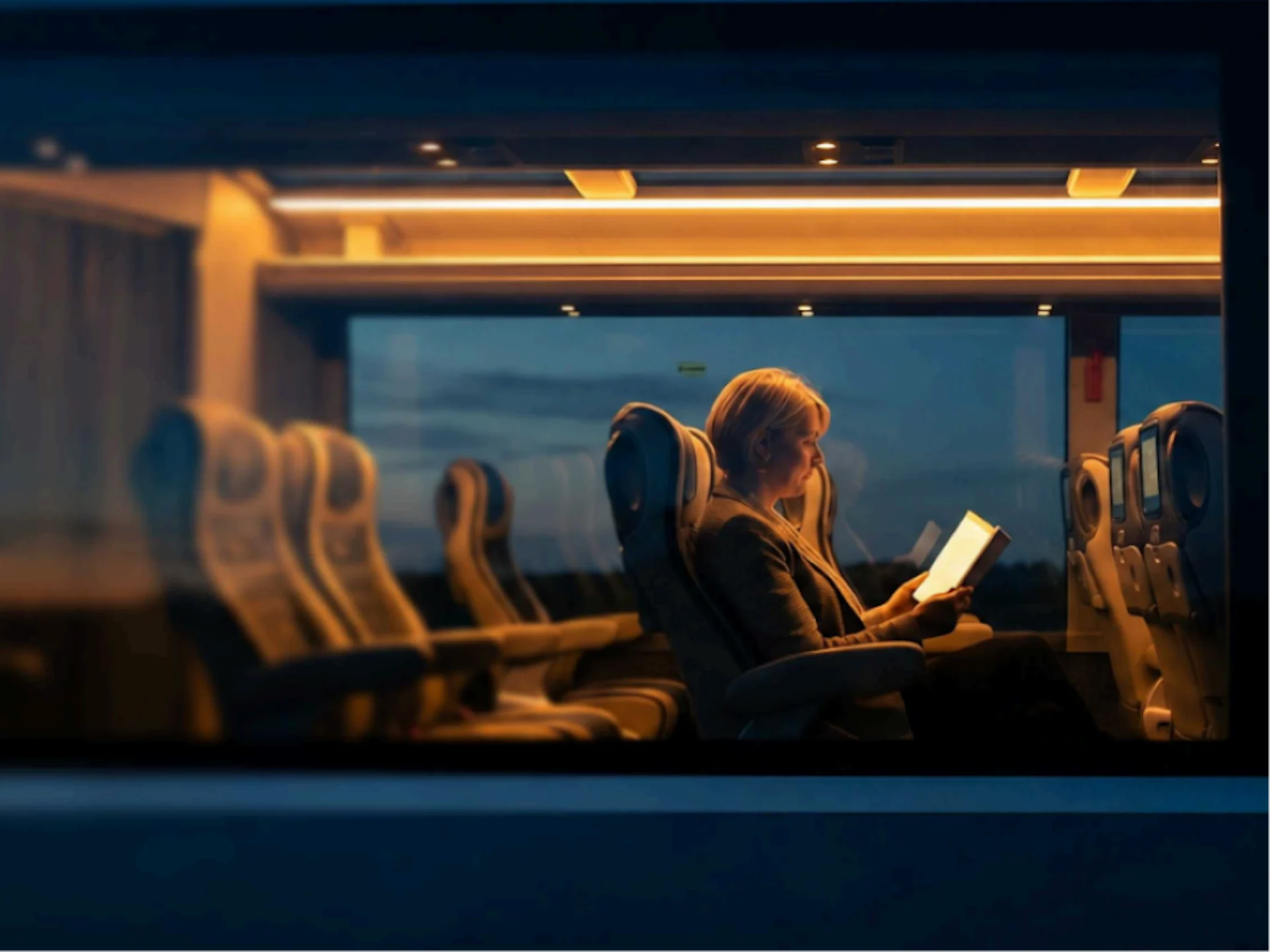 A passenger enjoying some personal time inside the Lumina coach at dusk